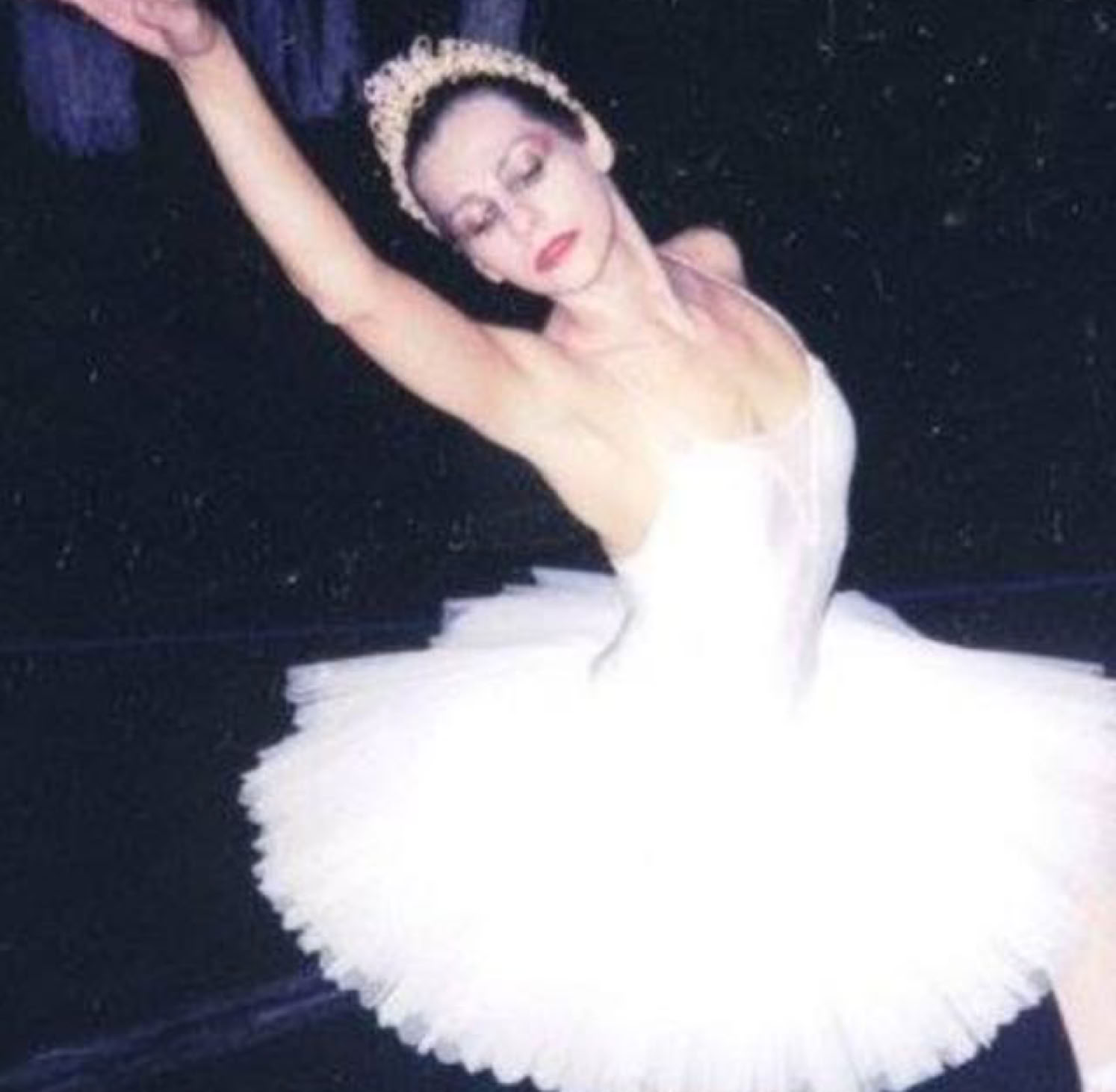 Danseuse en tutu blanc exécutant un mouvement du ballet "Le lac des cygnes" sur scène.